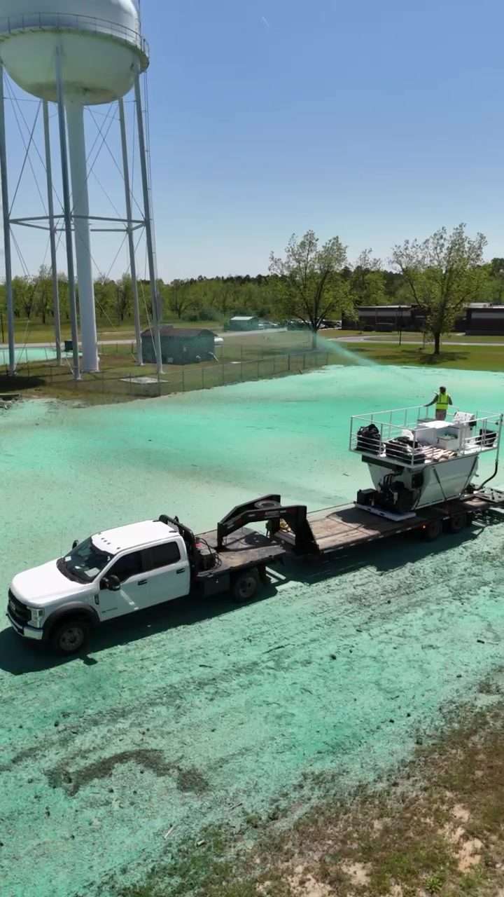 Aerial view of the TurfMaker 2200 hydroseeder spraying hydromulch near a water tower
